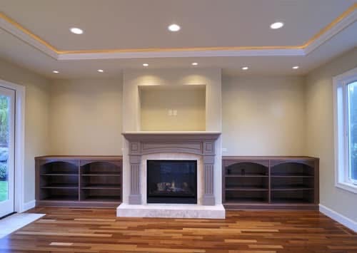 Finished living room with fireplace, built-in shelves and hardwood floors